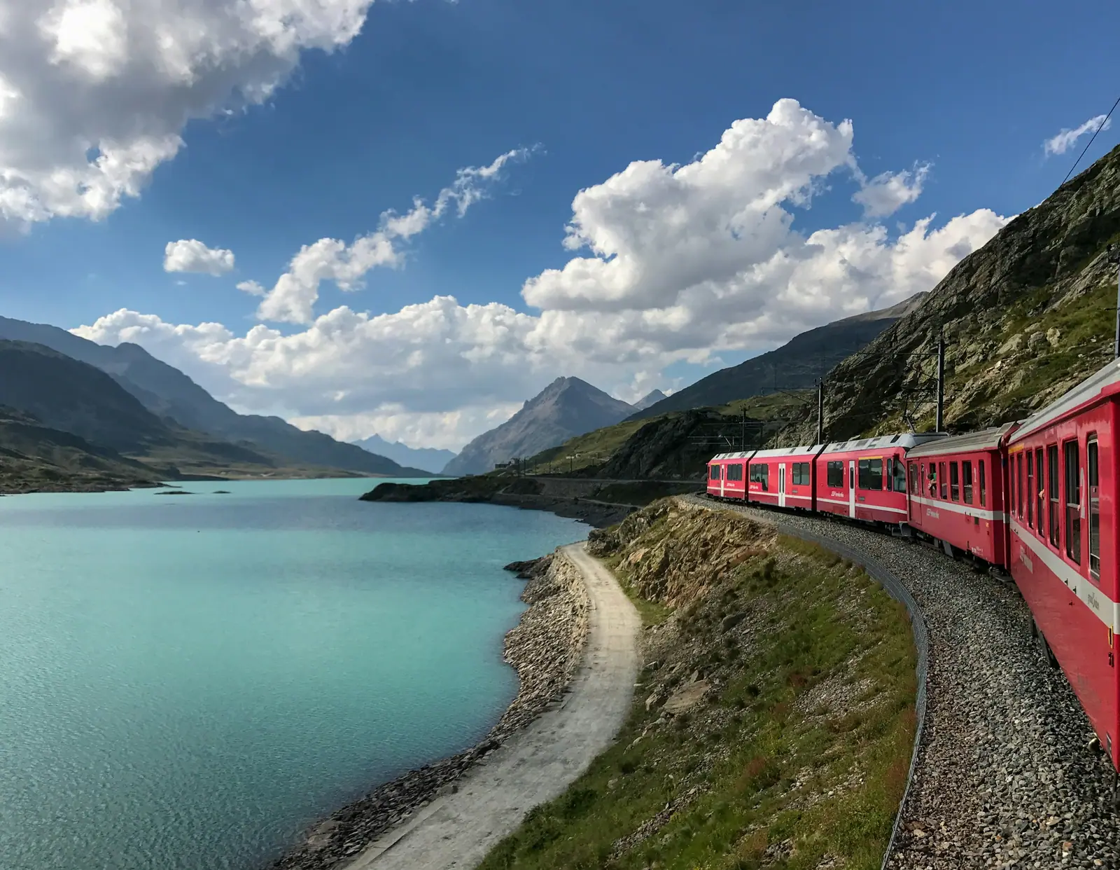 Ein roter Zug der Rhätischen Bahn fährt am Lago Bianco auf dem Berninapass entlang