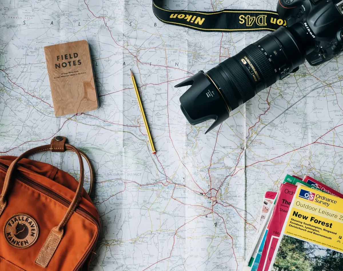 Landkarte, Notizbuch, Kamera und Reiseführer auf einem Tisch ausgebreitet