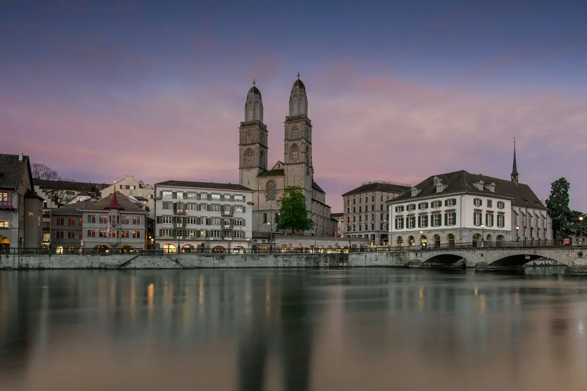 Das Grossmünster mit seinen Doppeltürmen am Limmatufer in der Abenddämmerung